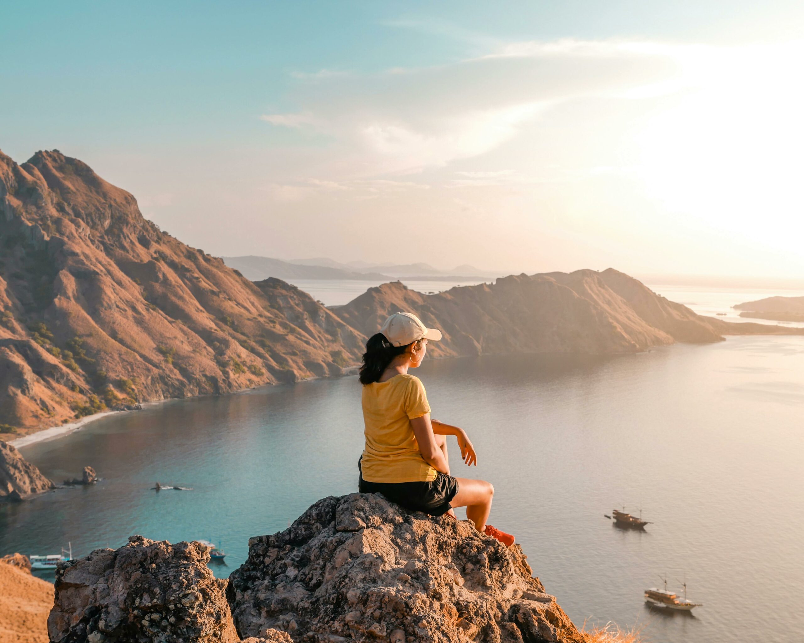 Woman enjoys a serene view of Komodo Island's rugged coastline at sunset, East Nusa Tenggara, Indonesia.