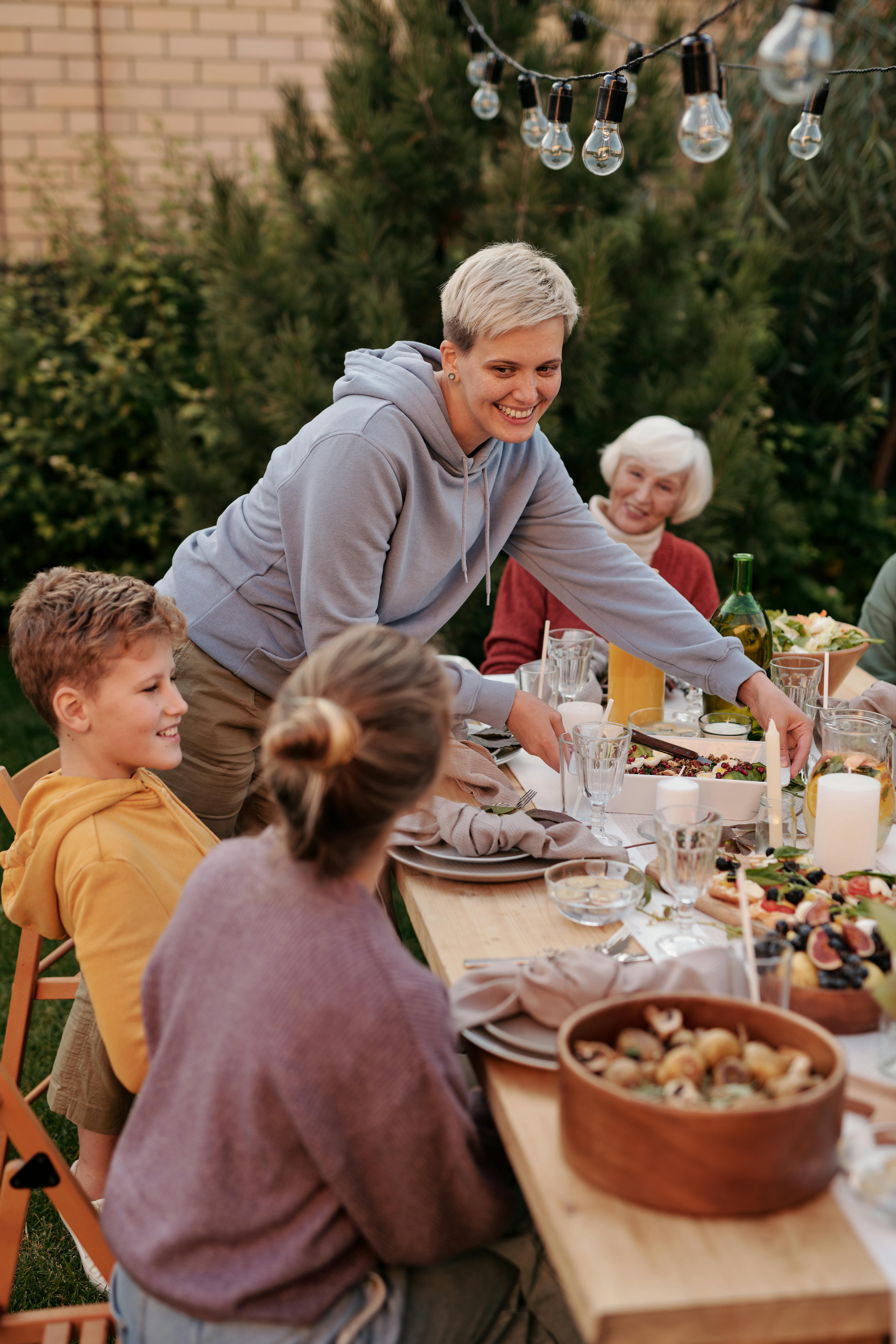A joyful family gathering enjoying dinner outdoors in a garden setting.